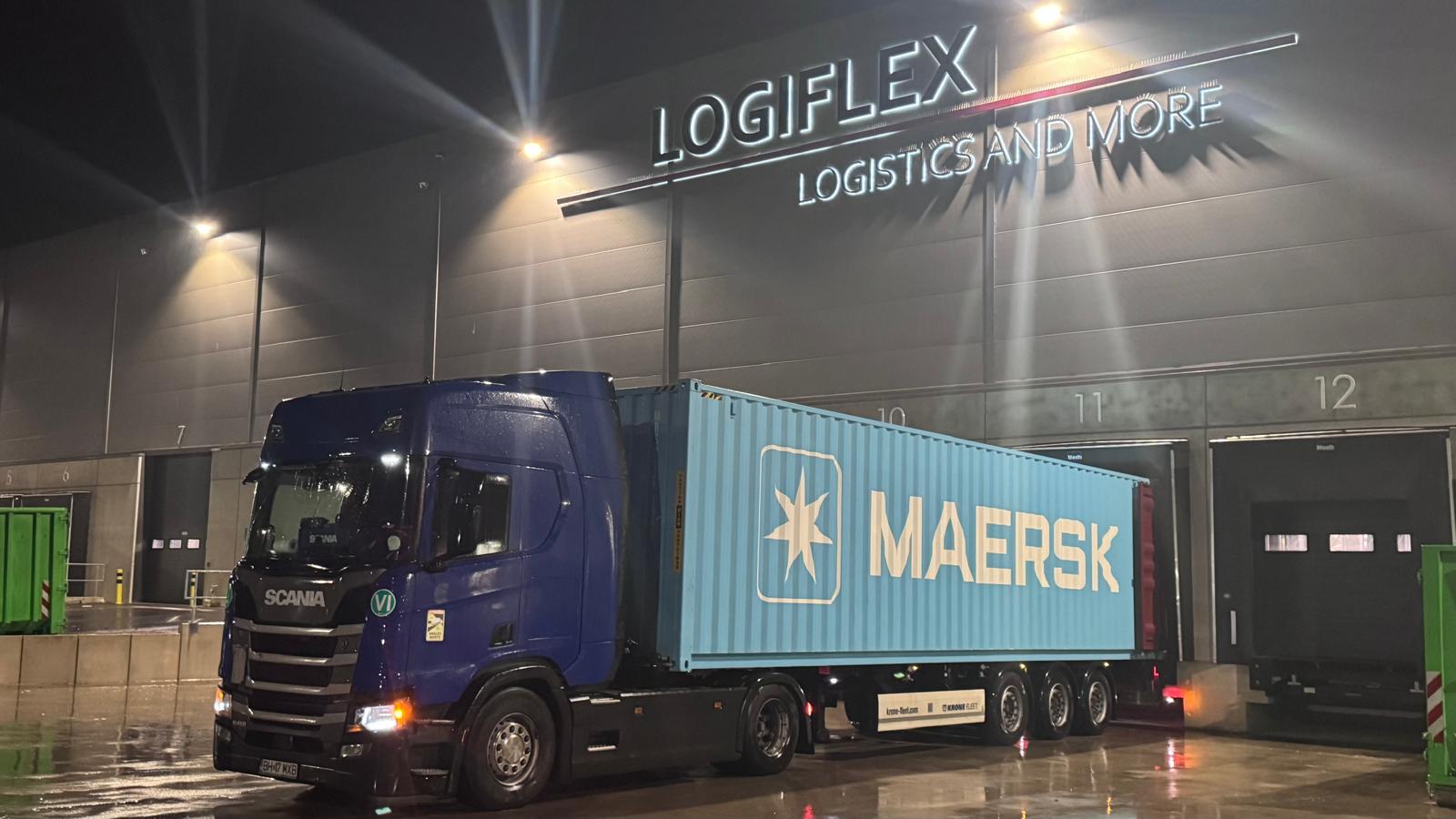 Camion Scania albastru cu semiremorcă portcontainer la un depozit logistic